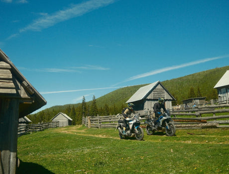 Adventure riders with their motorcycles among wooden barns in the Apuseni Mountains, Romania
